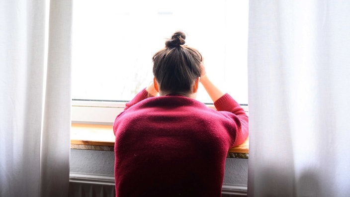 Symbolbild Einsamkeit: Eine Frau sitzt am Fenster und schaut hinaus.