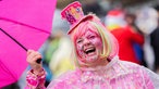 Eine Karnevalistin mit Regenschirn feiert an Weiberfastnacht die Eröffnung des Straßenkarnevals auf dem Alter Markt in Köln.