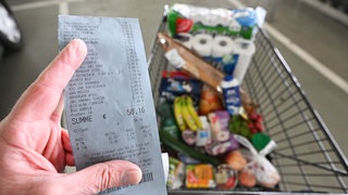 Ein Verbraucher hält nach einem Einkauf in einem Supermarkt einen Kassenzettel in der Hand.