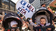 Archivbild: Auf einer Demo für mehr Kita-Plätze steht hinter zwei Kinderwagen ein Schild mit der Aufschrift "Ich will in die Kita".