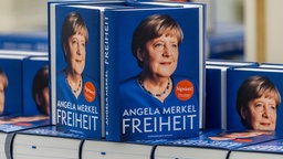 Mehrere Autobiografien "Freiheit im Deutschen Theater" von Angela Merkel liegen auf einem Tisch, 26.11.2024. 