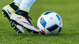 Blick auf Füße mit Fußballschuhen und einem Fußball.