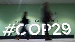 Während der COP29 laufen Menschen an einem COP29-Logo vorbei, Baku, Aserbaidschan, 14.11.2024.