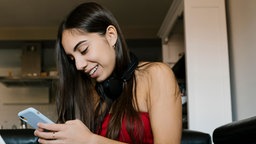 Mädchen mit Laptop und Mobiltelefon zu Hause sitzend auf dem Sofa.