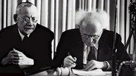 David Ben Gurion (r.) unterschreibt am 14. Mai 1948 in Tel Aviv die Unabhängigkeitserklärung Israels, neben ihm sitzt Rabbi Yehuda Hacohen 