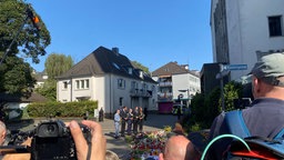 Mehrere Politiker stehen vor Blumenmeer und Pressevertretern