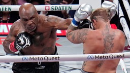 Mike Tyson trifft im Boxring seinen Gegner Jake Paul mit einer Geraden.