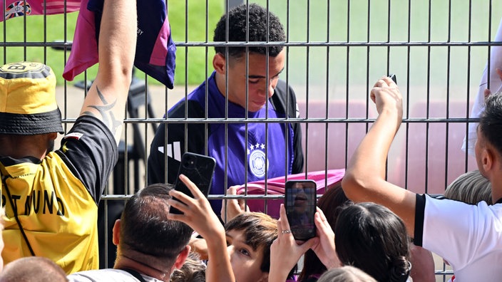 Jamal Musiala gibt nach dem öffentlichen Training Autogramme.