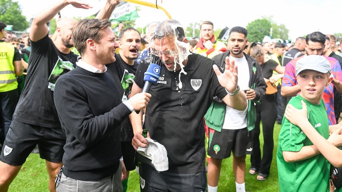 Münsters Trainer Sascha Hildmann bekommt nach dem Aufstieg die obligatorische Bierdusche.