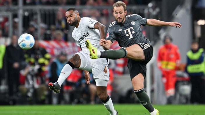  Münchens Harry Kane (r) kommt gegen Leverkusens Jonathan Tah zum Schuss.