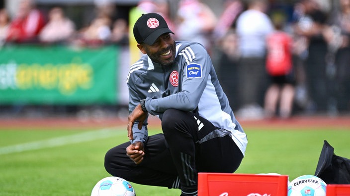 Daniel Thioune, Trainer von Fortuna Düsseldorf, kniet am Rande eines Testspiels an der Seite