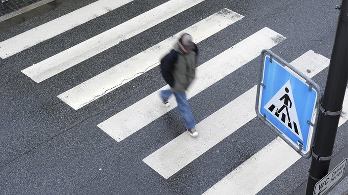 Mann geht über einen Zebrastreifen