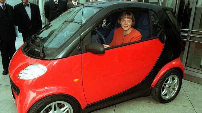 Bundesumweltministerin Angela Merkel 1998 in rot-schwarzem Smart vor Bonner Bundeskunsthalle