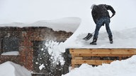 Ein Mann schippt am Samstag (25.12.2010) im brandenburgischen Sieversdorf (Oder-Spree) Schnee von einem Dach