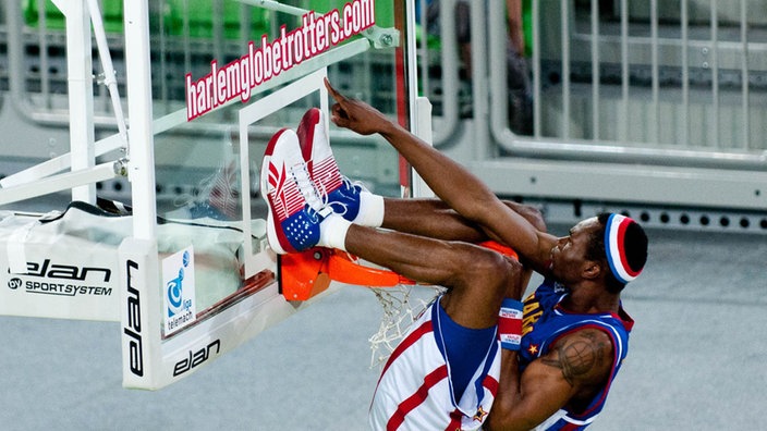 Spieler der Harlem Globetrotters hängt unter dem Basketball-Korb