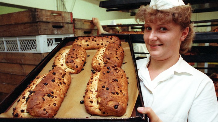 Bäckerin hält Blech mit Chrisstollen hoch