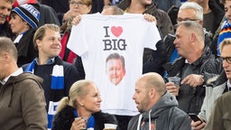 HSV-Fußball-Fan hält T-Shirt mit Aufdruck „I (Herz) Big“ hoch