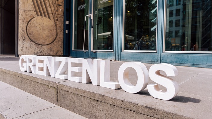 Foto von weißen Buchstaben "grenzelos" auf Treppe positioniert. 