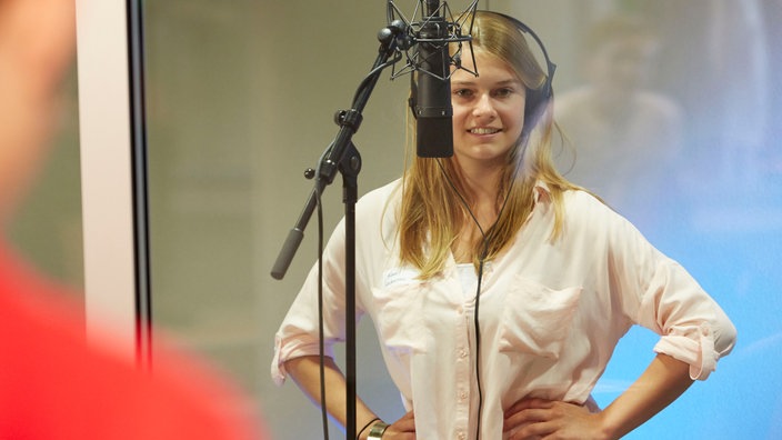 Schülerin steht mit Kopfhörer vor einem Mikrofon im WDR STUDIO ZWEI