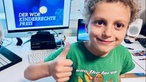 Junge hebt Daumen und sitzt am PC-Schreibtisch