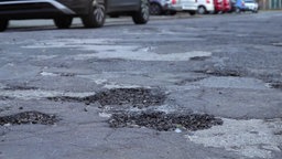 Das Bild zeigt drei Schlaglöcher auf einer Straße.