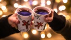 Zwei Becher mit Glühwein, die aneinander stoßen