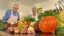 Martina und Moritz in ihrer Küche, im Vordergrund Kürbis, Zwiebeln und weitere Gemüsesorten