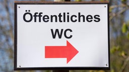 Ein Schild, welches zu einem öffetnlichen WC führt