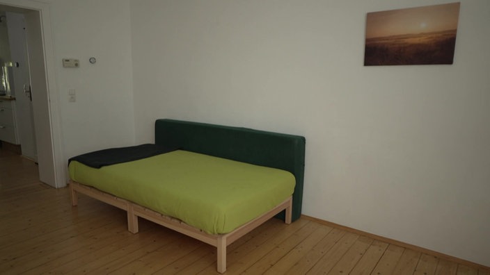 Das Bild zeigt ein Zimmer mit einem Bett und einem Tisch.