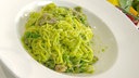 Tagliolini mit Erbsen und Schinken in einem tiefen Teller angerichtet