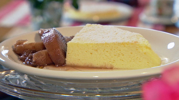 Ein heller Kuchen auf einem weißen Teller garniert mit Pflaumenmus.