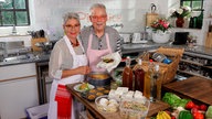 Martina und Moritz bereiten in ihrer Küche Gerichte zum Mitnehmen zu