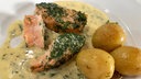 Lachs mit Kartoffeln in der Schale und Soße auf einem Teller angerichtet