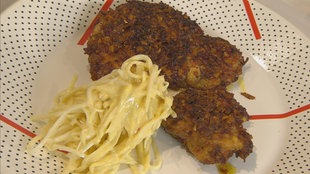 Kaninchenschnitzel mit Gemüse-Chips-Hülle und einem Rohkostsalat aus Sellerieknolle auf einem Teller angerichtet