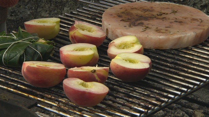  Pfirsichhälften auf einem Grillrost, daneben liegt ein Salzstein