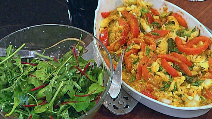 Spätzle Caprese in einer Schüssel angerichtet, daneben eine Schüssel Salat