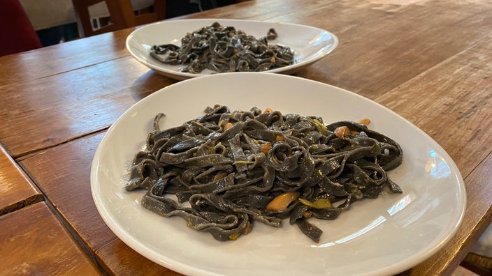 Tagliolini neri al ragù di seppie auf einem weißen Teller angerichtet.