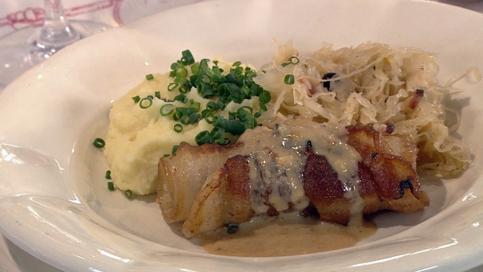 Ferkesbuchrouladen mit Sauerkraut und Püree auf einem Teller angerichtet