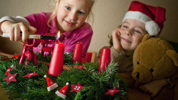 Kind zündet erste Kerze am Adventskranz an