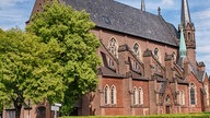 Seitenansicht von St. Marien Eschweiler, einer Kirche aus rotem Backstein vor blauem Himmel