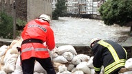 Feuerwehrleute legen im September im Eifel-Städtchen Monschauauf einer Brücke über die Rur Sandsäcke bereit, 1998